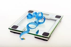 weighing scale used by humans with a blue measuring tape